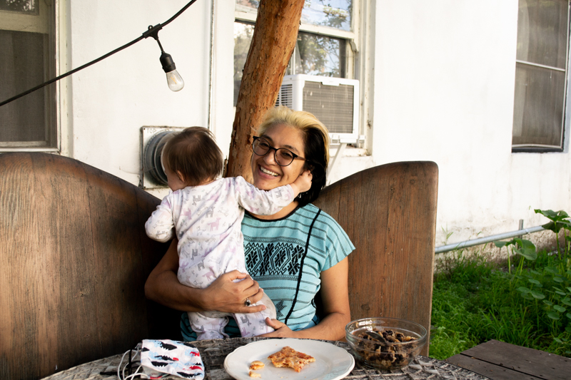A woman sits in a backyard with her baby.